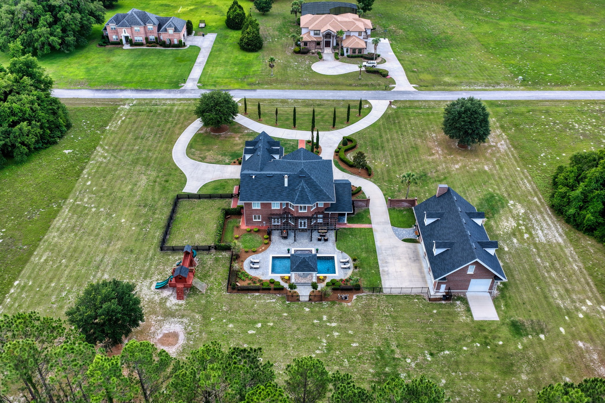 Aerial drone view of brick estate with pool, guest house, and acreage