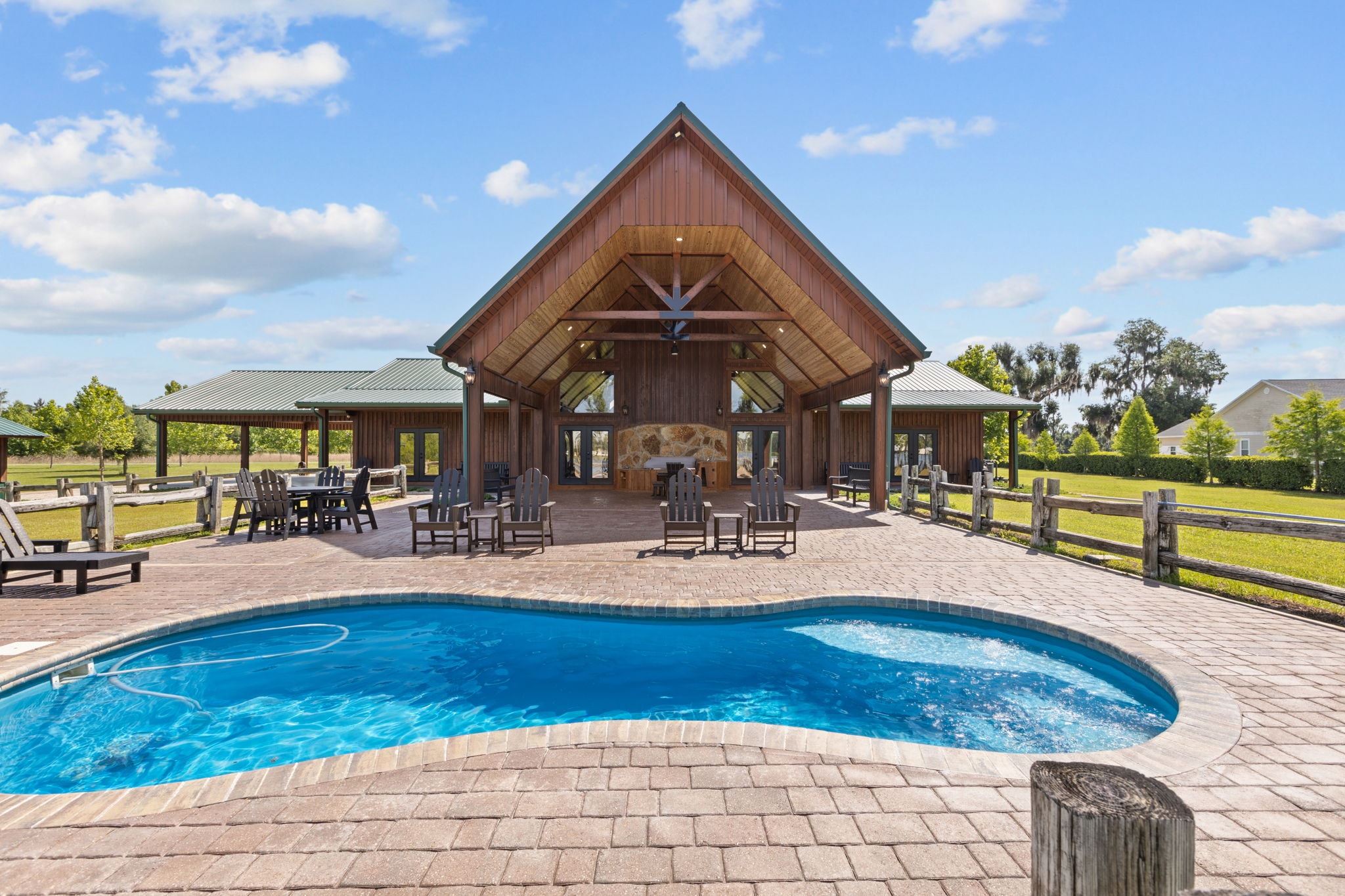 Timber-frame pavilion with vaulted cedar ceiling, stone fireplace, freeform pool, and open pasture