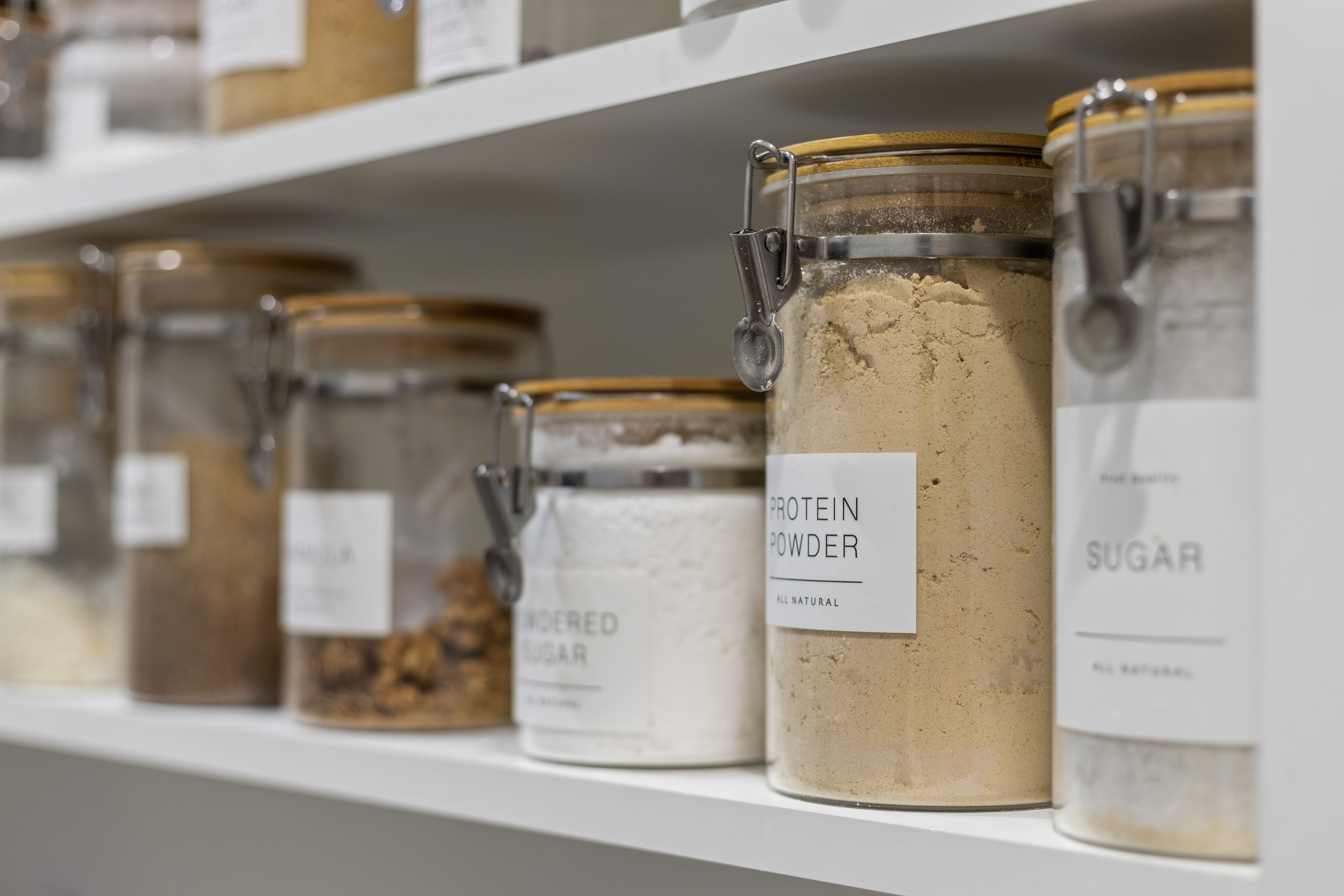 Styled pantry shelves with labeled glass storage jars and bamboo lids