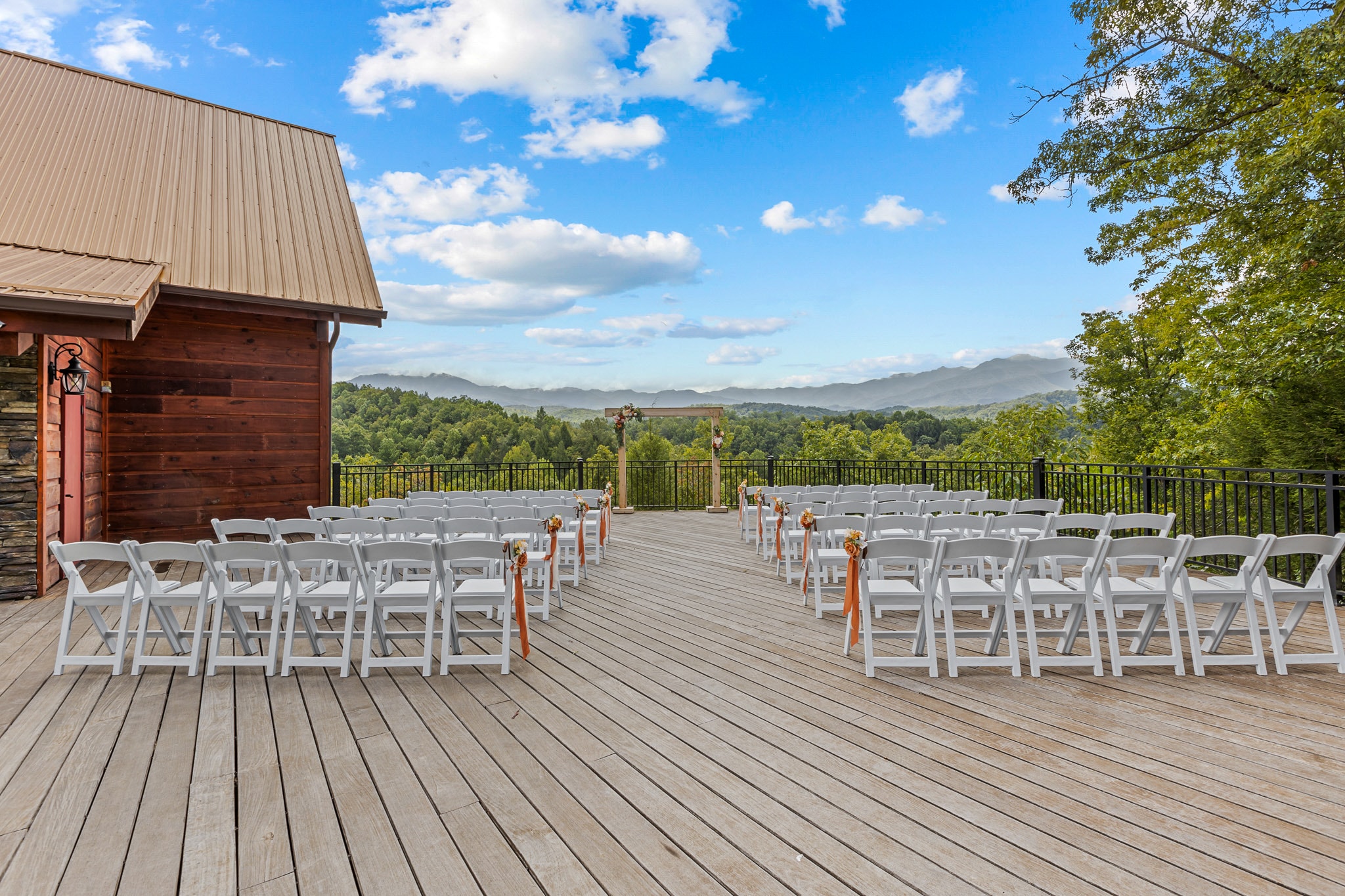 Outdoor wedding venue at twilight with white ceremony chairs, timber-frame chapel, and dramatic sky